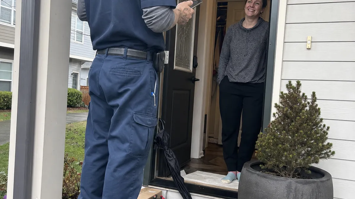 A plumber greeting a homeowner at their front door with a digital customer profile overlay