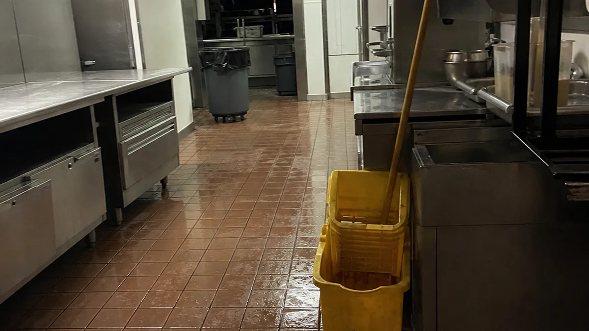 A smartphone glowing with a call on a counter in a dark restaurant kitchen